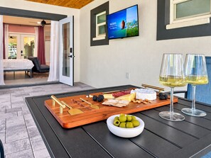 Ein Zimmer mit Essbereich, gedecktem Tisch und Speisen wie Käse, Oliven sowie Gläsern mit Weißwein.