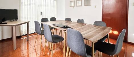 Una sala de conferencias con una mesa de madera, sillas grises, un televisor y una puerta.