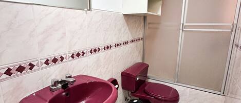 Un baño con lavamanos pedestal, inodoro y cabina de ducha.