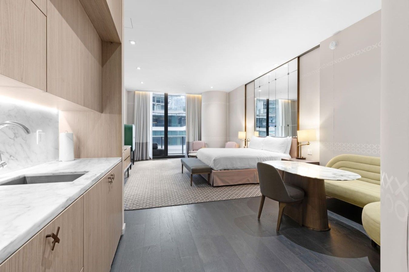Een moderne hotelkamer met een marmeren badkamer, een zithoek en een groot bed.