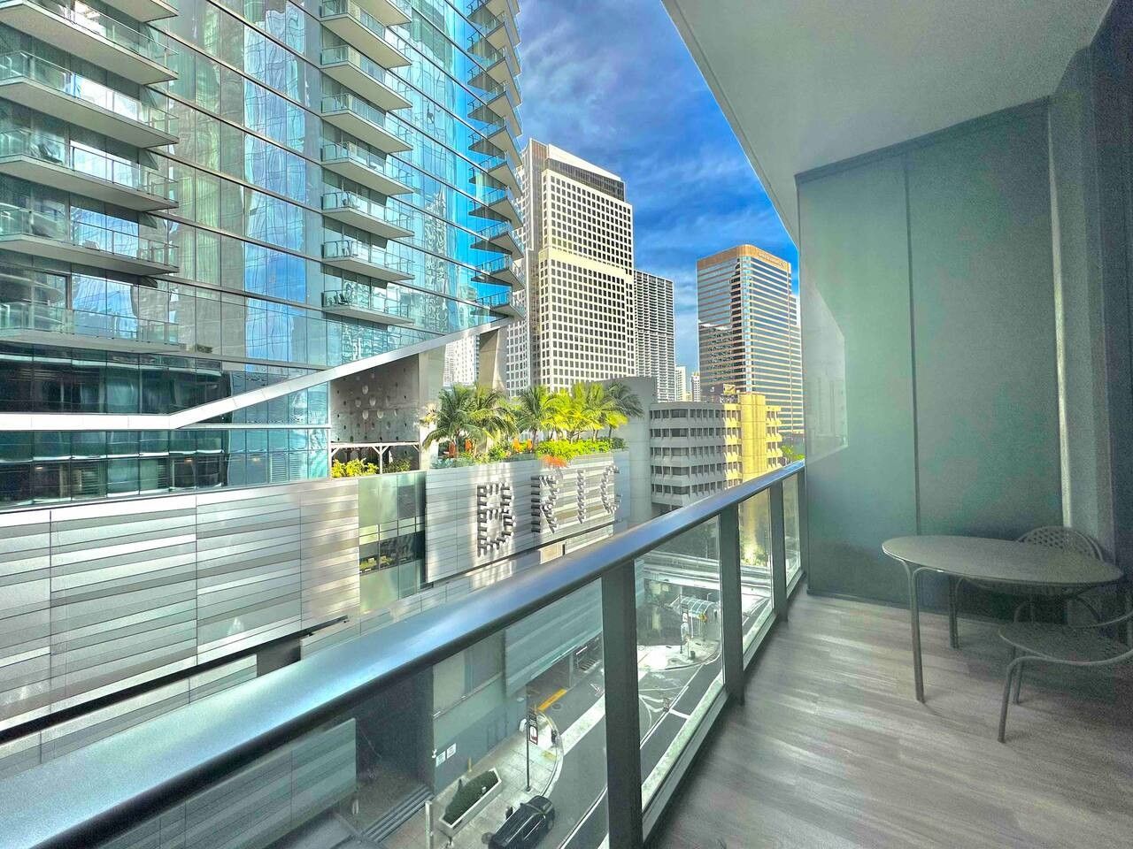 Een modern interieur met een balkon en uitzicht op een stadsgezicht, met een glazen balustrade en een zithoek.