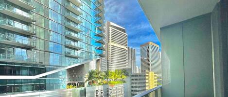 A modern interior with a balcony overlooking a cityscape, featuring a glass railing and a seating area.