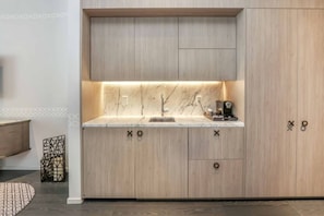 A modern kitchen with a marble backsplash, wooden cabinets, and a coffee machine. - Stunning King Suite Brieckell (Miami)