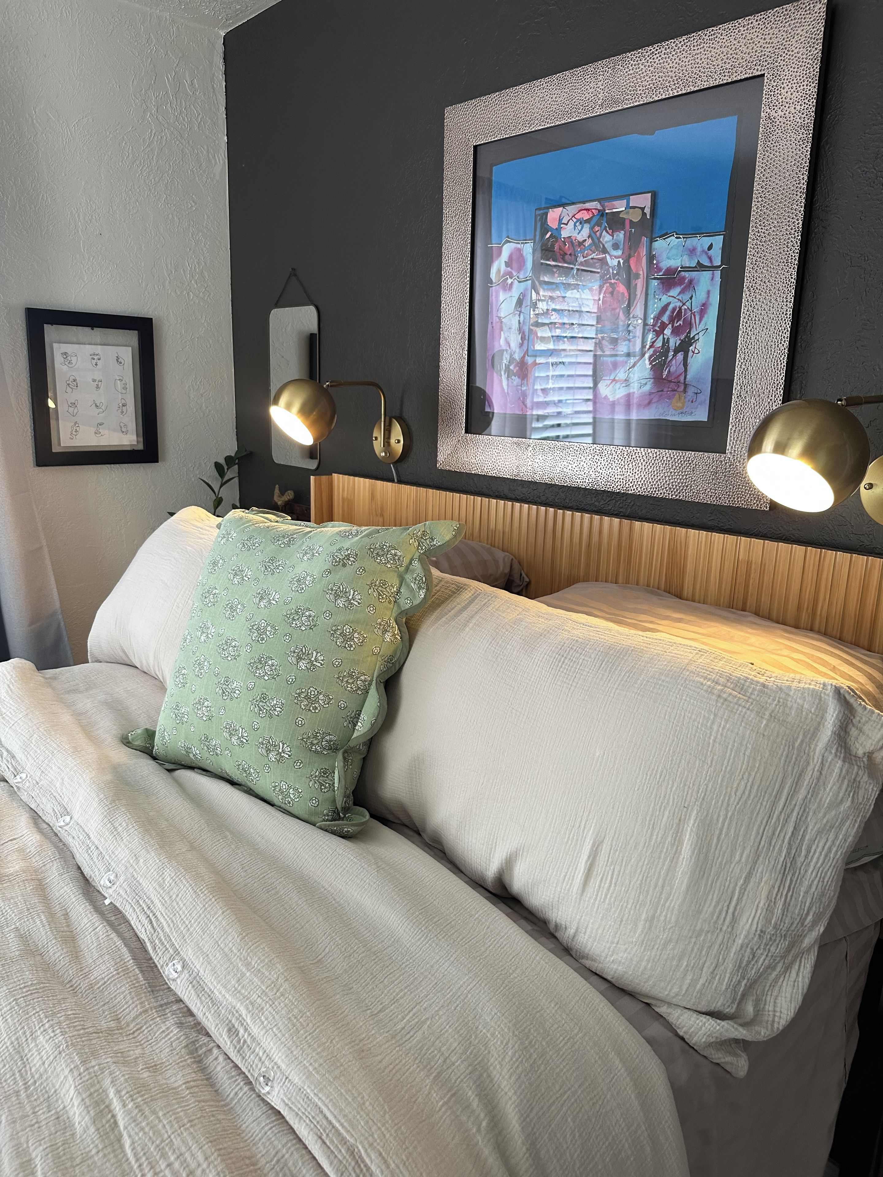 A bed with a headboard, two wall-mounted lamps, and a framed artwork above the bed.