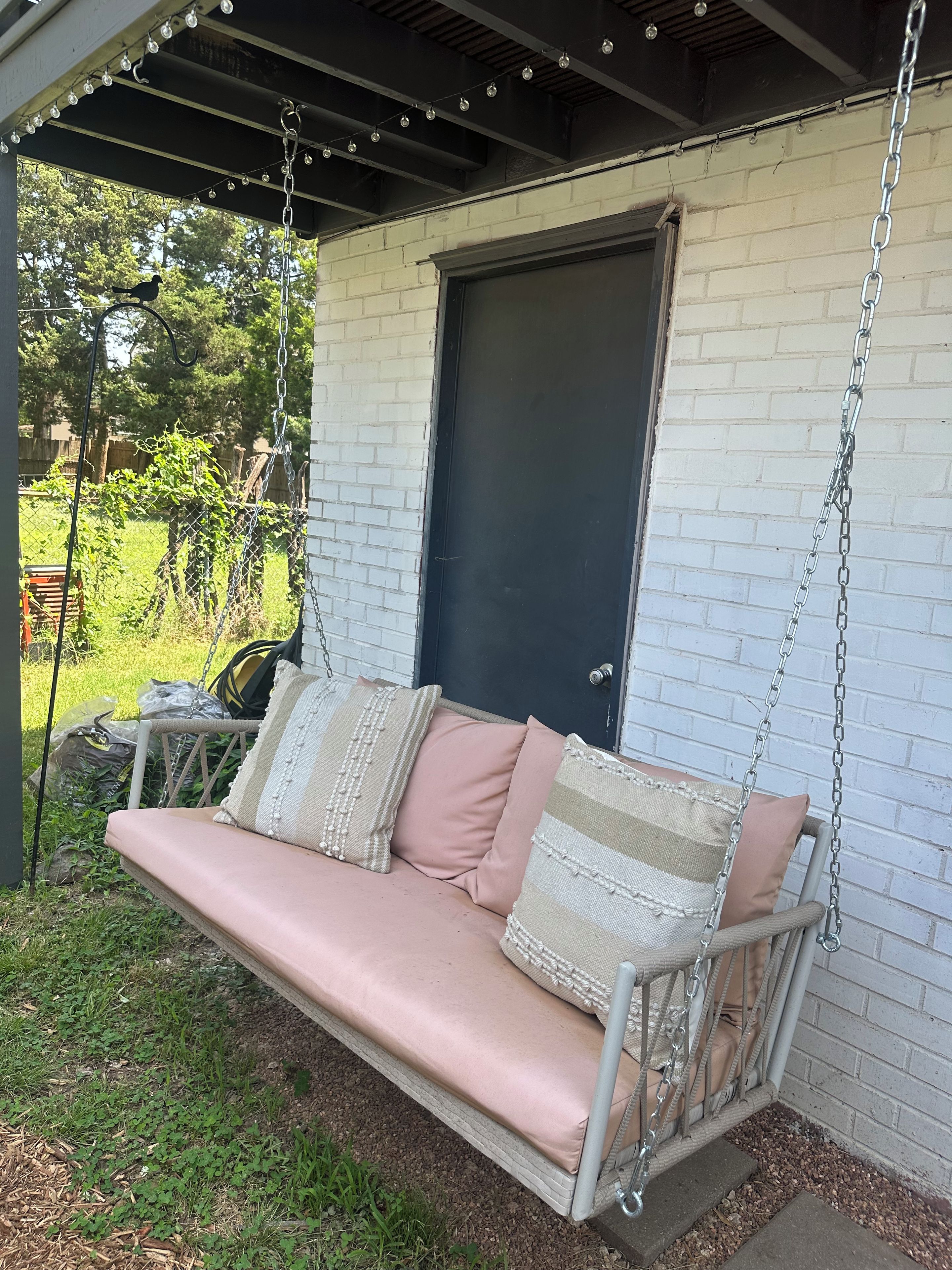 A porch with a swing seat, a black door, and a chain overhead.