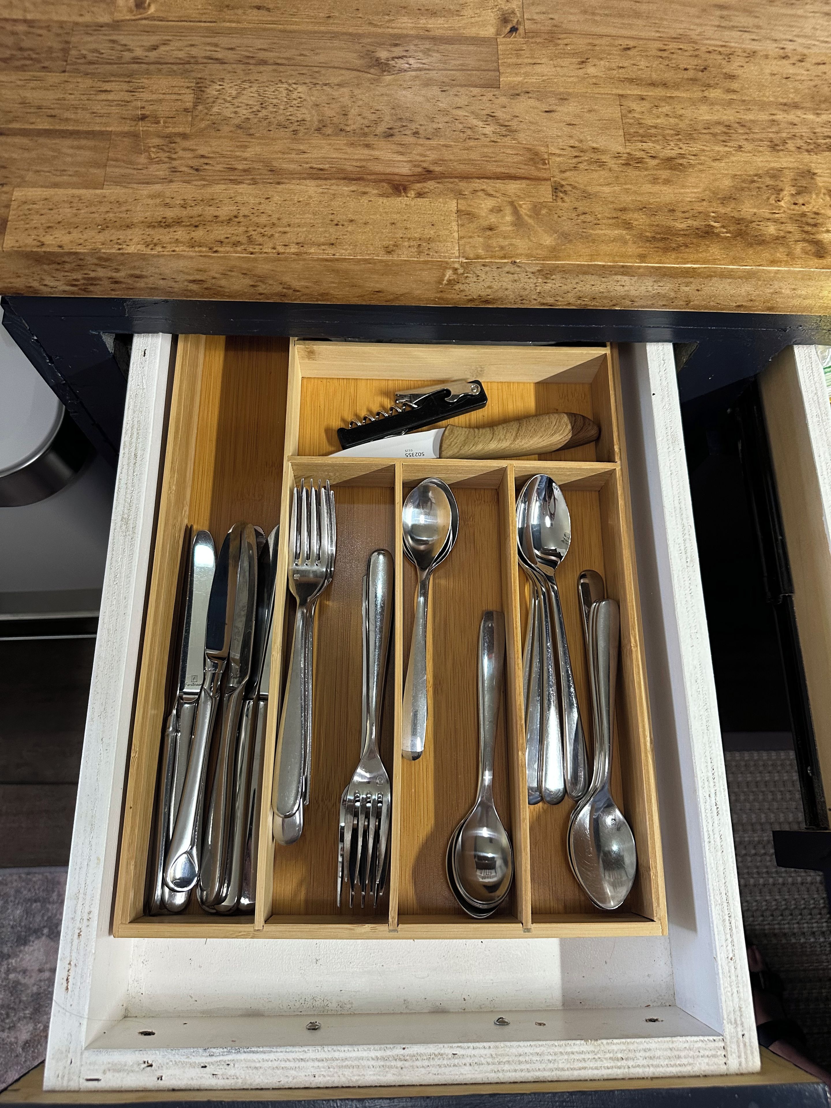 A drawer with compartments containing various cutlery items.