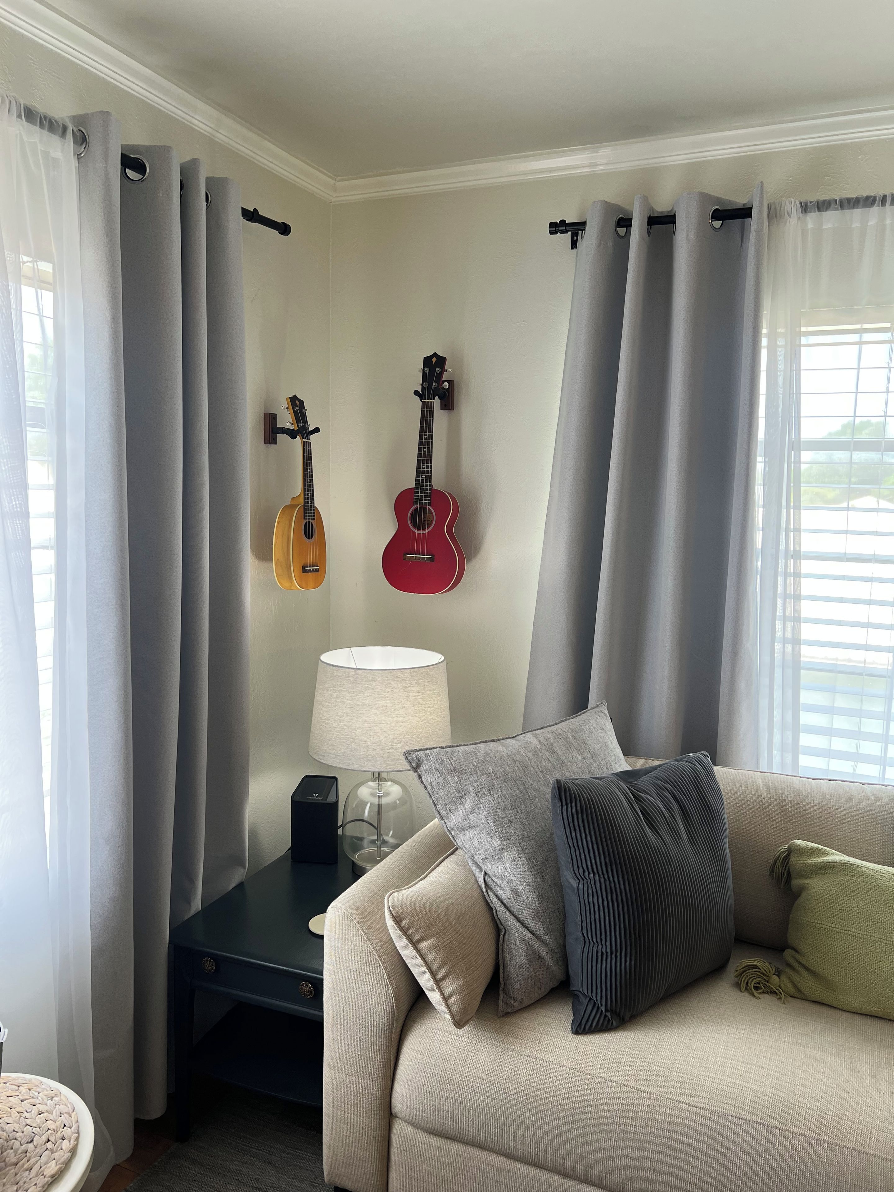Un salon avec un canapé, une lampe et deux guitares accrochées au mur.
