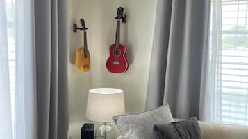 Un salon avec un canapé, une lampe et deux guitares accrochées au mur.