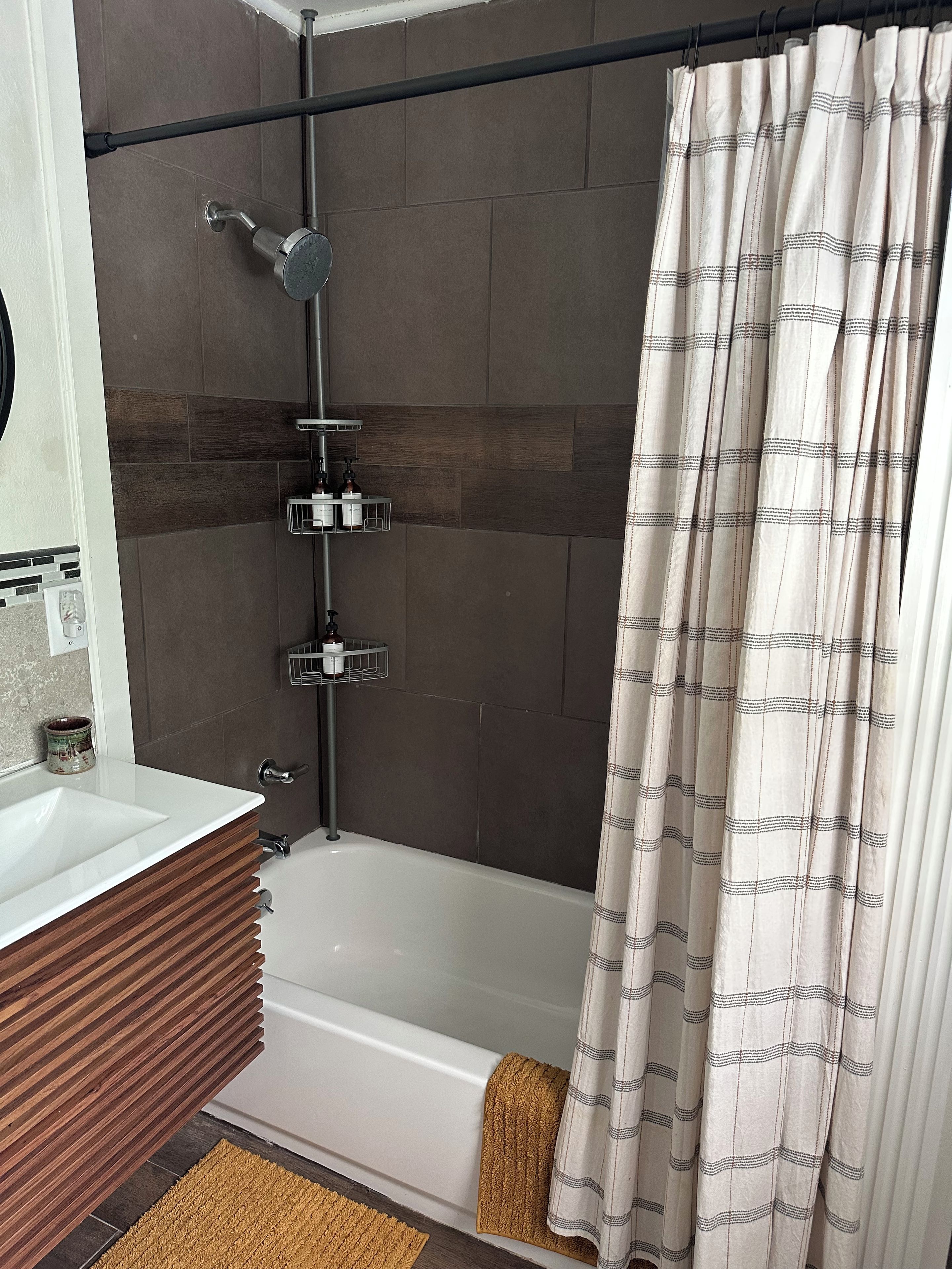 Une salle de bain avec une baignoire, une douche, un meuble-lavabo avec un miroir et un porte-serviettes.