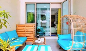 A modern interior with a wooden bench, a wicker chair, and a small table with cups and a teapot. - 1BR Premium Suite w Patio (Paranaque)