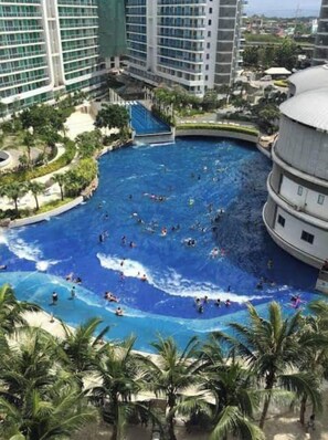 A large indoor swimming pool surrounded by palm trees and modern buildings. - 2BR Tropical Scandi Suite (Paranaque)