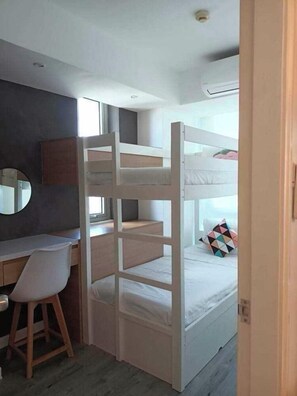 A bunk bed with a desk and chair, a round mirror, and a window. - 2BR Tropical Scandi Suite (Paranaque)