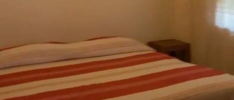 A bedroom with a bed, a nightstand, and a framed picture on the wall.