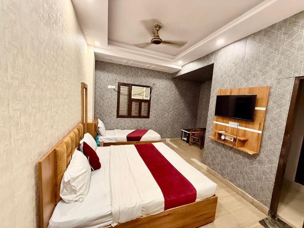 Une chambre d’hôtel avec deux lits, un téléviseur fixé au mur et un ventilateur de plafond.