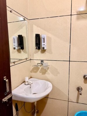 A bathroom with a white sink, a mirror, and two soap dispensers mounted on the wall. - RAJ by Vaishno Miles (Haridwar)