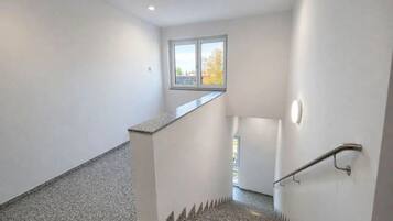 Eine Treppe mit Handlauf, einer kleinen Aussichtsplattform und einem Fenster für natürliches Licht.