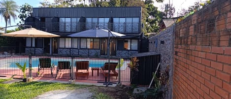 A two-story building with a swimming pool and outdoor seating.