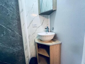 A bathroom with a marble wall, a wooden vanity, and a white sink. - Güigüa Apart-Hotel (Puerto Iguazú)