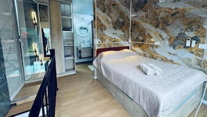 Una camera d'albergo con un letto, uno specchio, un armadio e un bagno con doccia.