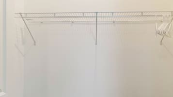 Een kamer met een witte muur, een houten vloer en een metalen rek.