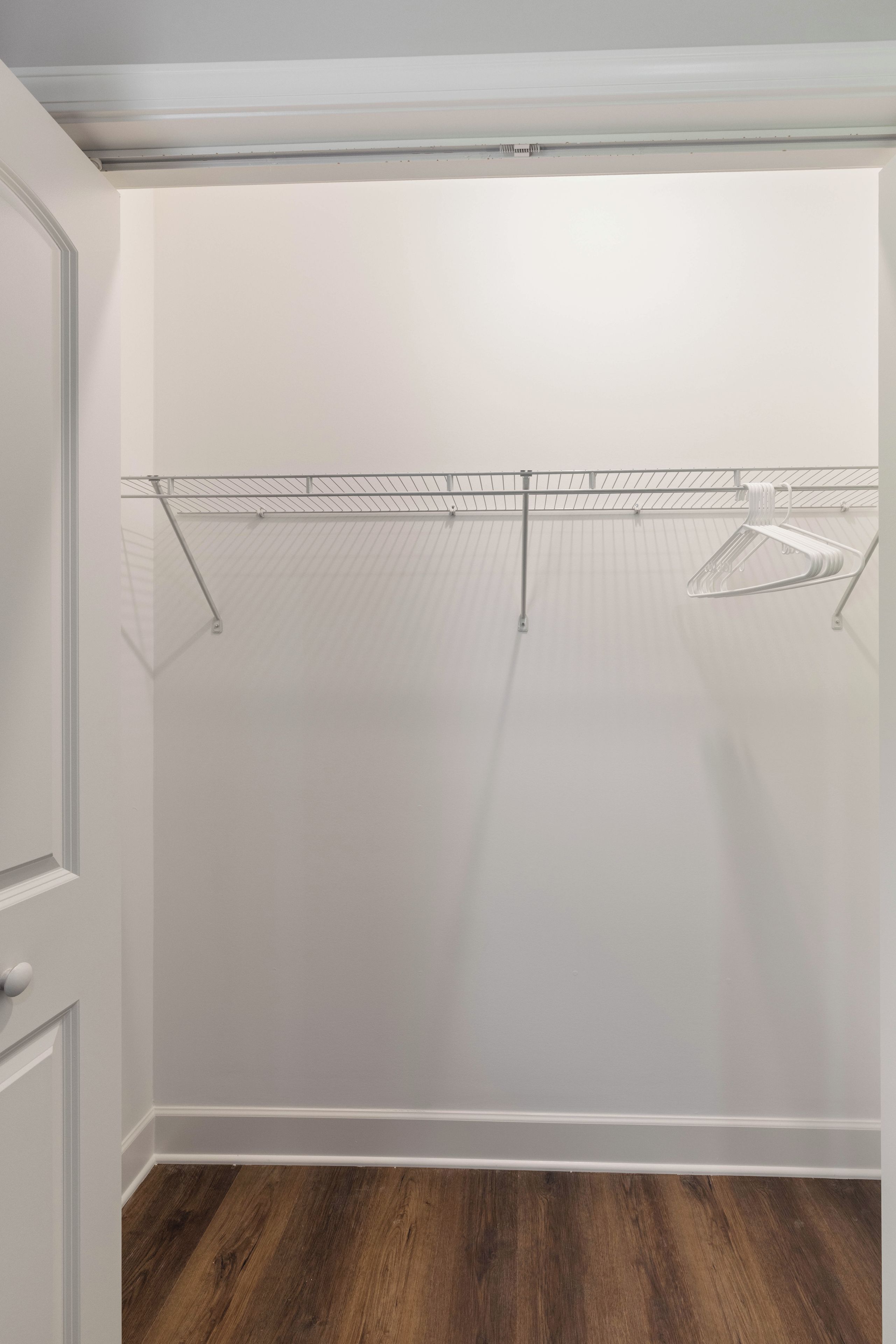 Een kamer met een houten vloer, witte wanden en een metalen rek.