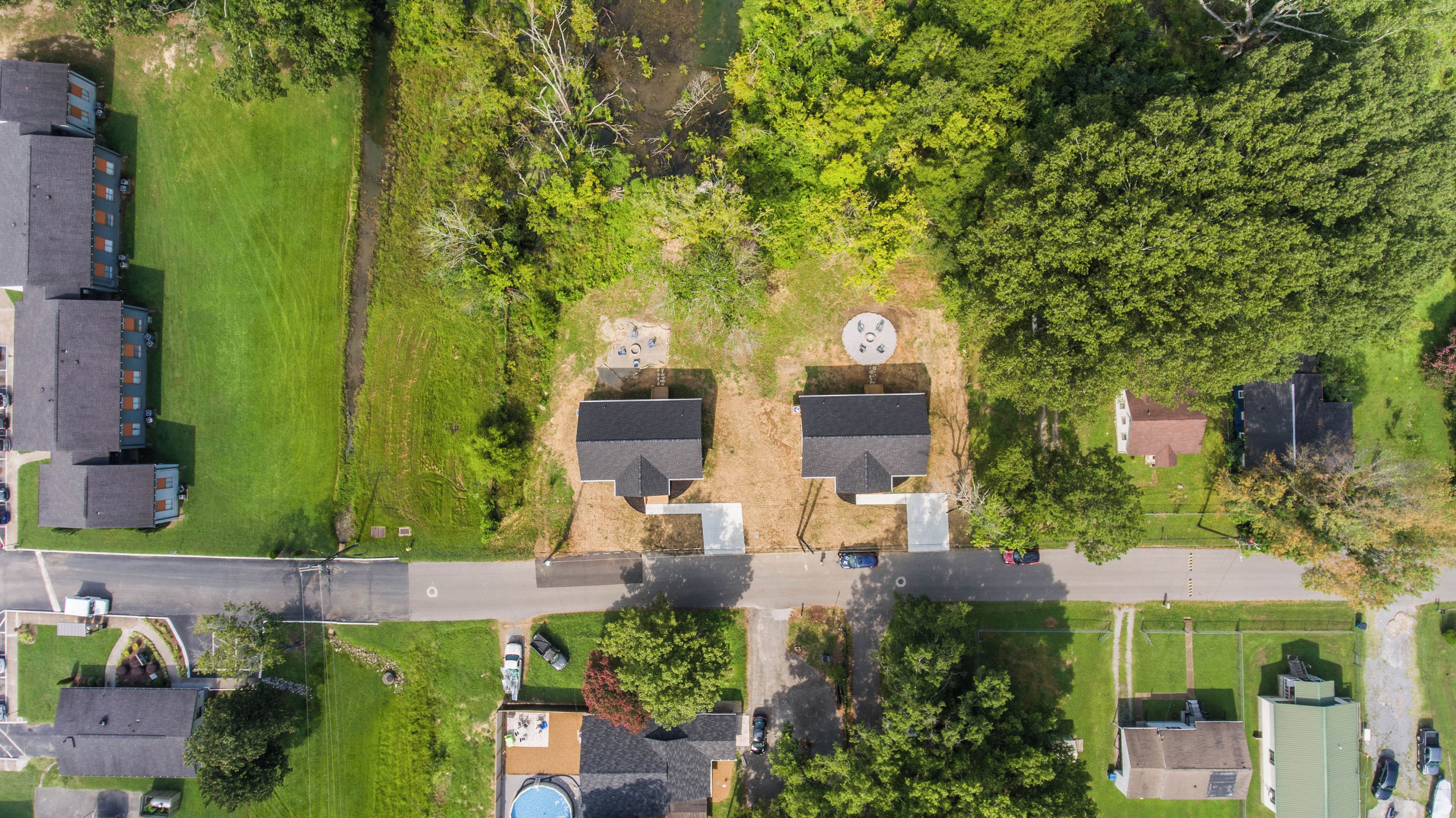 An aerial view of a residential area with houses, a road, and green spaces.