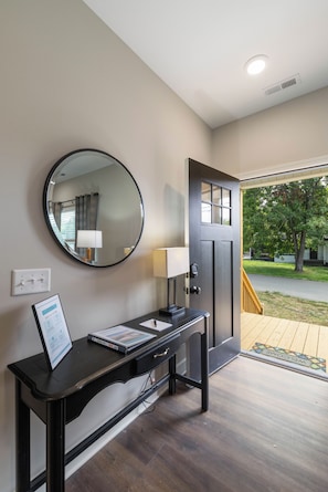 Une salle de bain moderne avec un grand miroir rond, un lavabo et une porte donnant sur un balcon.
