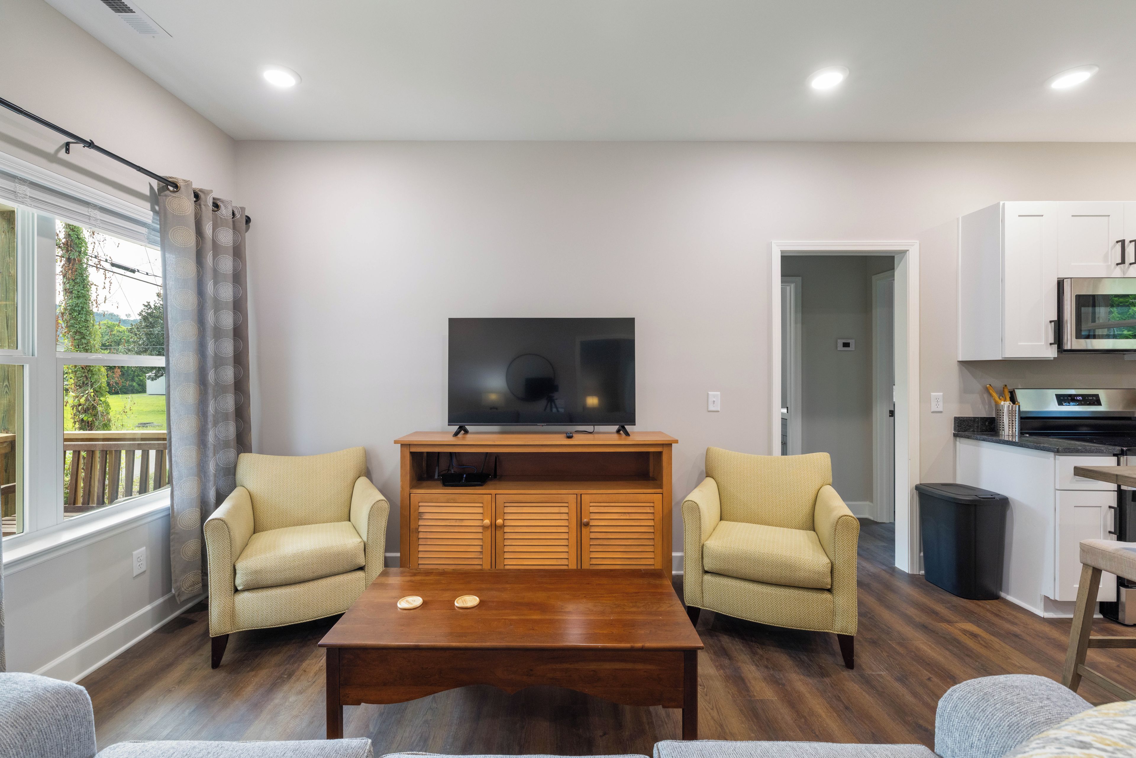 A living room with a TV, two armchairs, a coffee table, and a view of the outdoors.