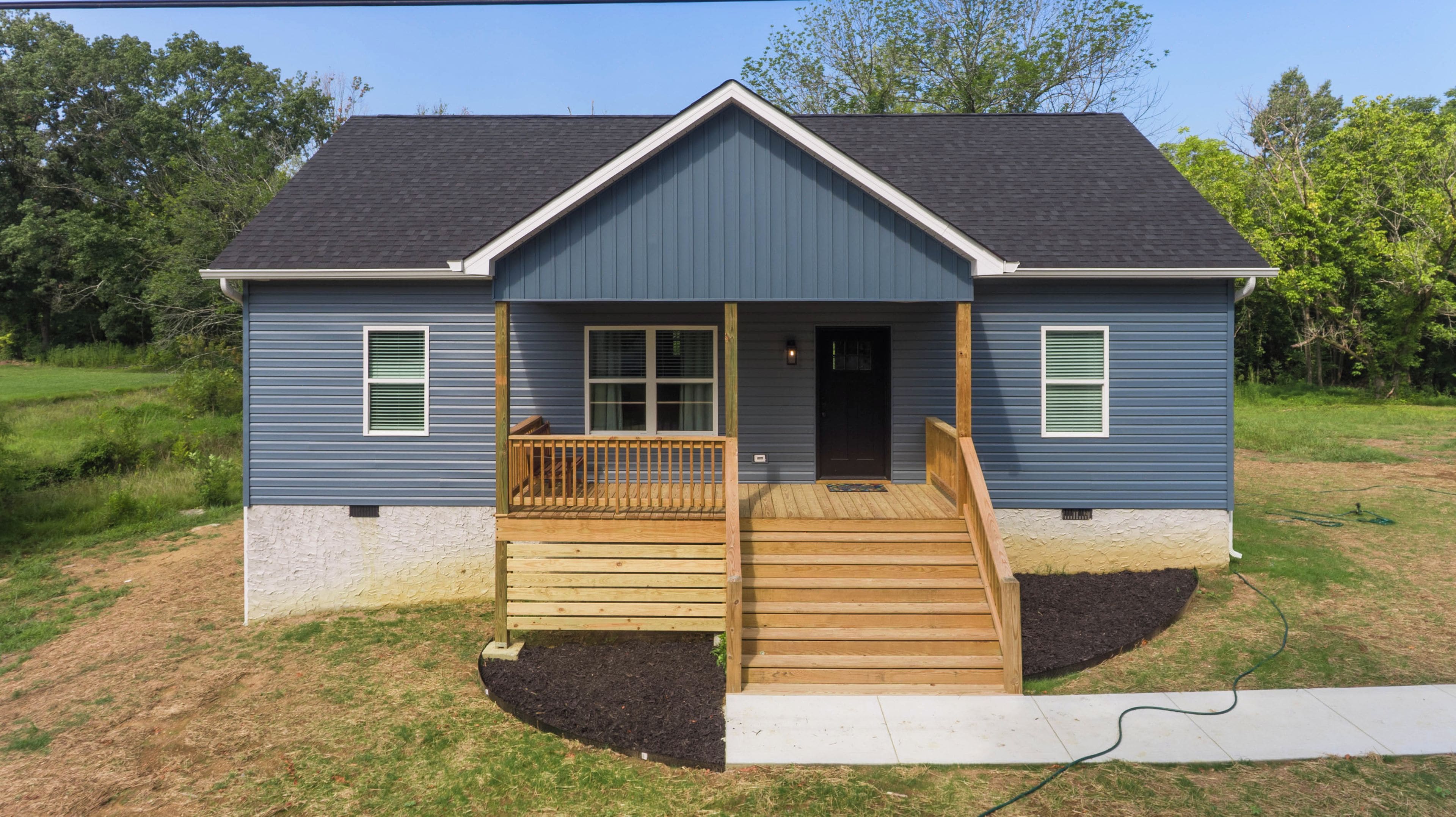 A two-story house with a front porch, a wooden staircase, and a small deck.
