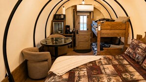 Habitación pequeña con una cama litera, una mesita con silla, microondas y cafetera.
