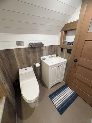 A compact bathroom with a toilet, sink, and storage cabinet.