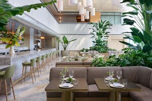 A modern restaurant with a bar area, seating arrangements, and indoor plants. - Ocean Views w/ Free Parking (Miami)