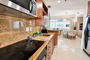 Cozinha moderna com bancadas de granito, eletrodomésticos de aço inoxidável e uma área de jantar com mesa e cadeiras.