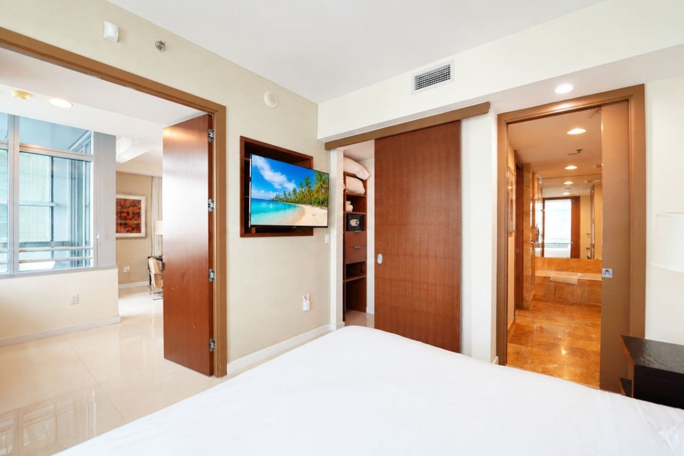 A hotel room with a large bed, a television, a wardrobe, and a bathroom visible through an open door.