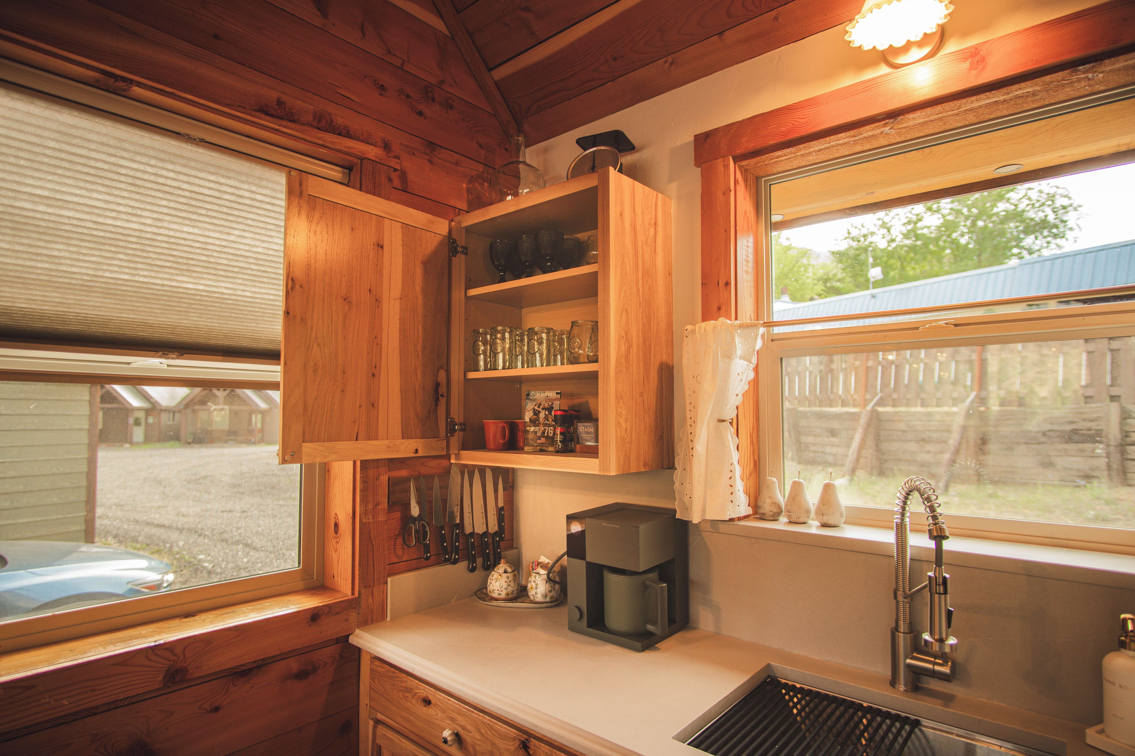 A wooden kitchen with a window, a coffee maker, and a knife block.
