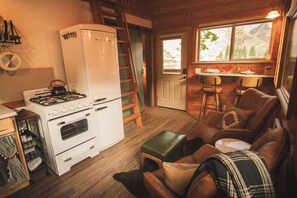 Ein gemütliches Ferienhäuschen im Inneren mit Küchenzeile, inklusive Herd, Kühlschrank und Holzboden.