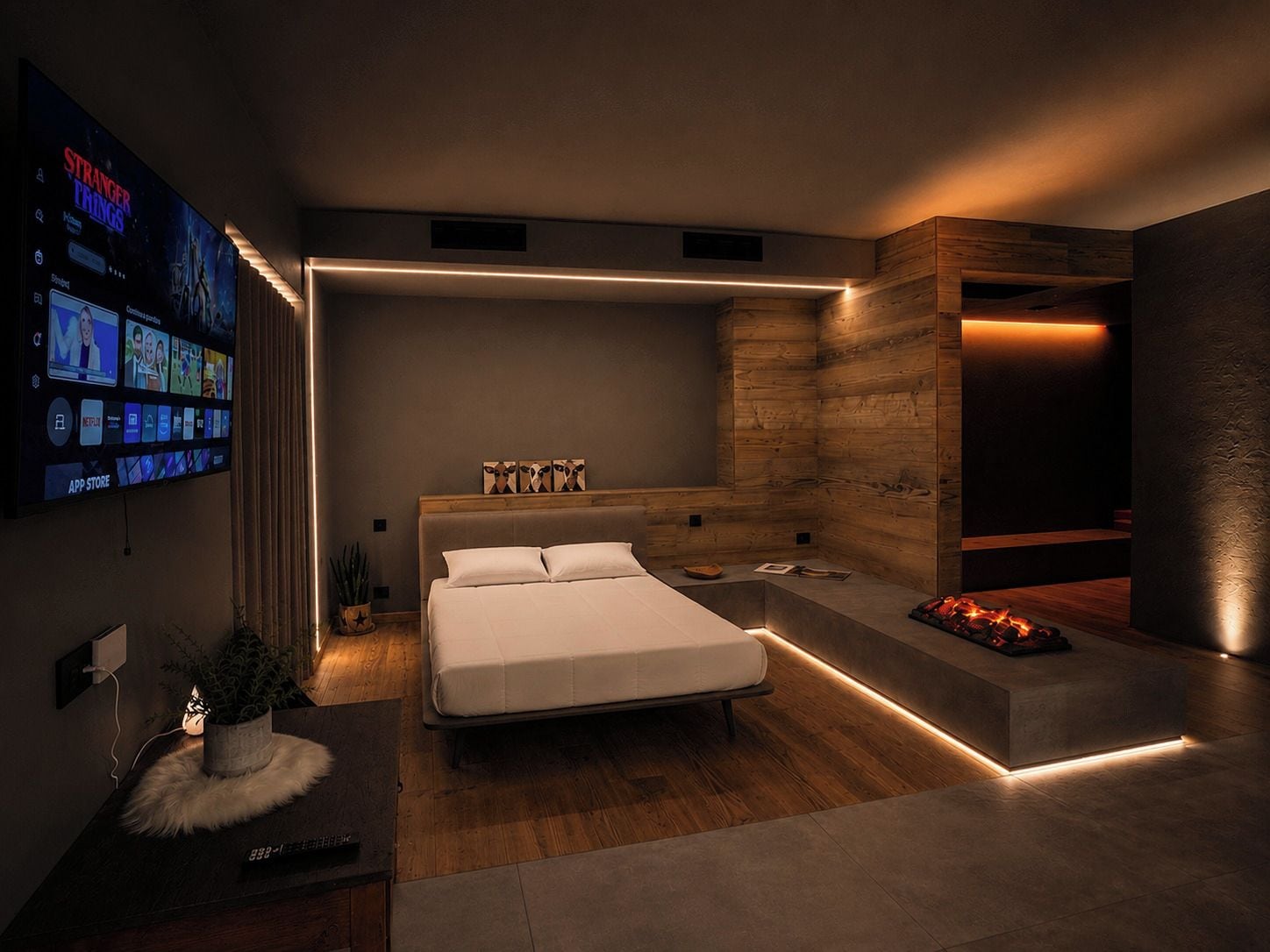 A modern bedroom with a large bed, a TV mounted on the wall, and a built-in bench with a fire feature.
