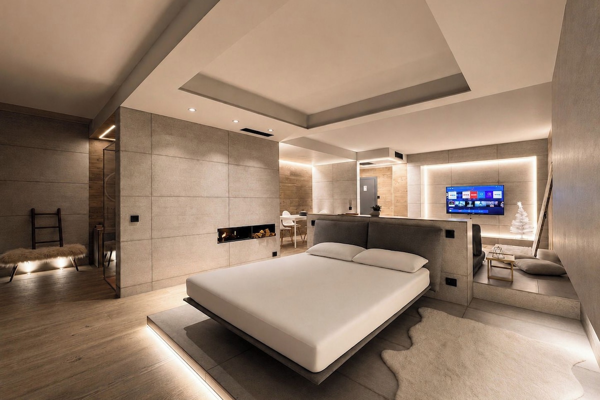 Quarto moderno com cama grande, TV integrada e lareira.