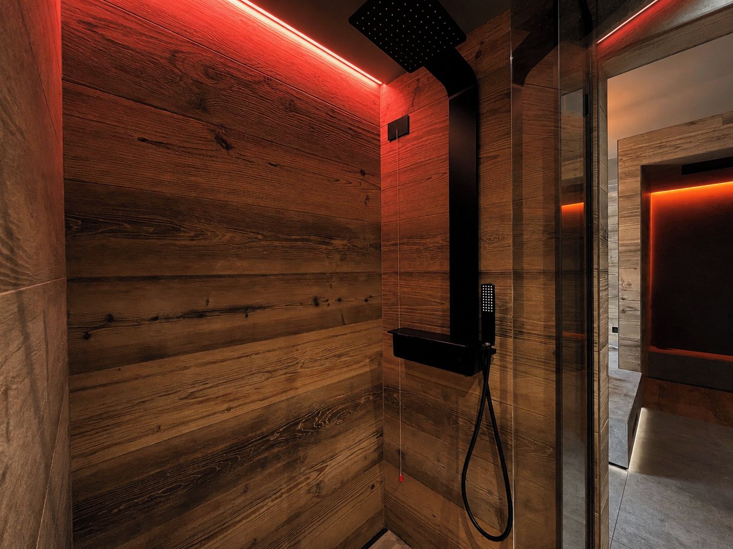 A sauna with wooden walls and a black showerhead.