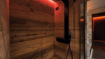 A sauna with wooden walls and a black showerhead.