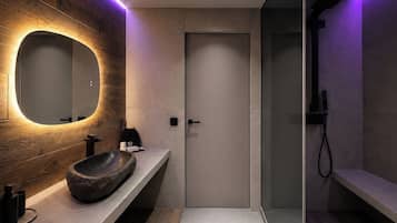 A modern bathroom with a round mirror, a stone basin, and a shower area.