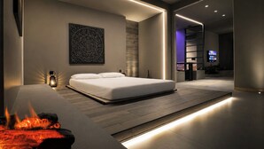 A modern bedroom with a bed, a wall-mounted artwork, and a built-in fireplace. - Agarthi Suites (Piateda)