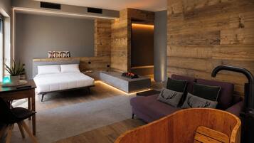 A modern bedroom with a bed, a sofa, a wooden bathtub, and a small table with a plant.