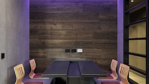 A conference room with a dark wooden wall, a long table, and two chairs with cushioned seats. - Agarthi Suites (Piateda)