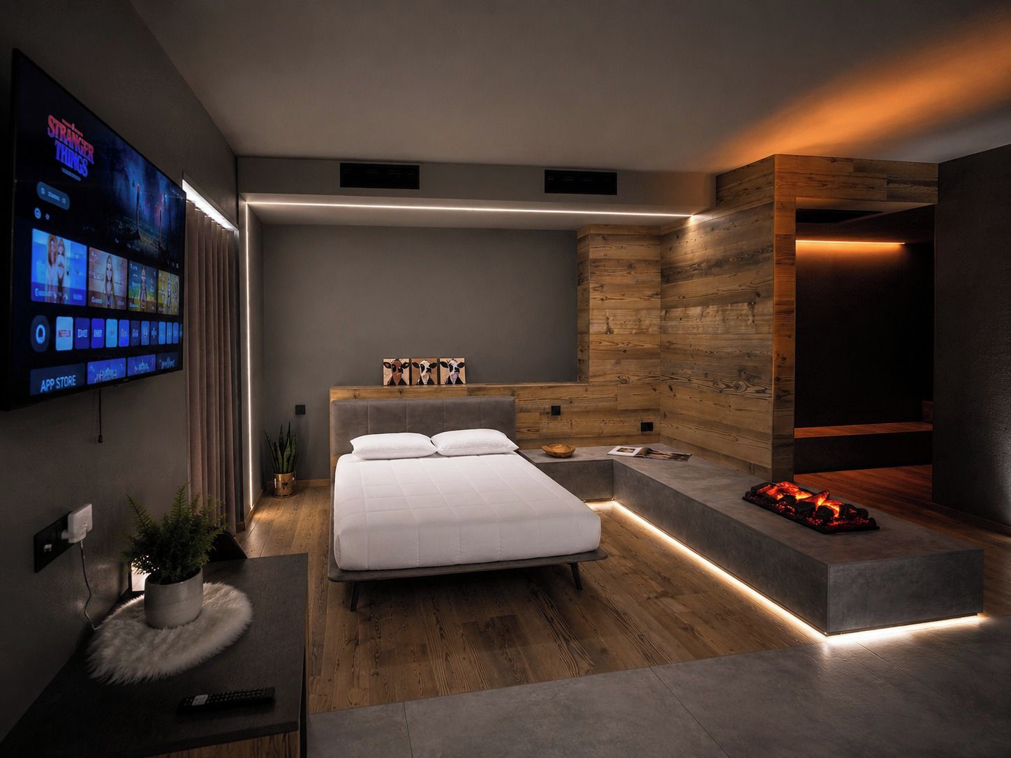 A modern bedroom with a bed, a TV mounted on the wall, and a built-in fireplace.