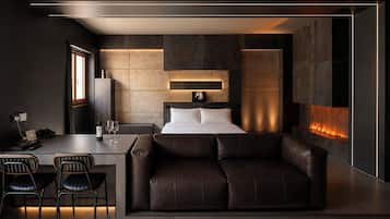 Ein modernes Schlafzimmer mit einem Bett, einem Sofa, einem Schreibtisch mit Stühlen und einem Kamin.
