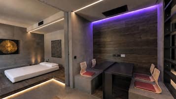 Een moderne badkamer met een bad, een douchegedeelte, en een zithoek met stoelen.