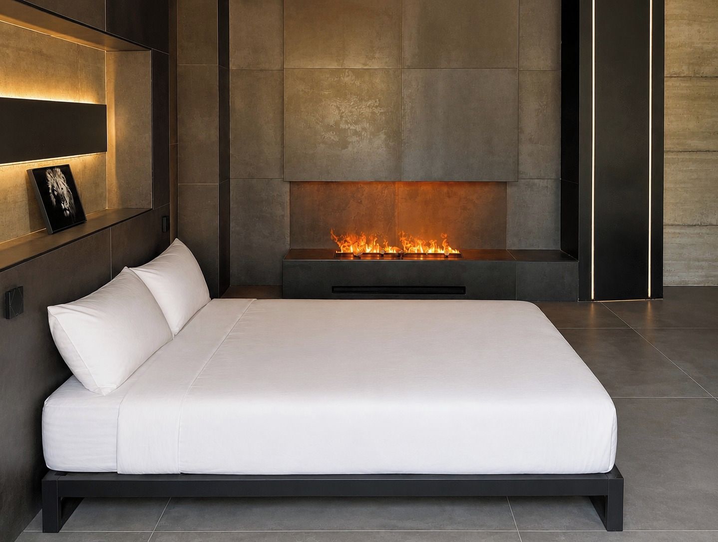 Un dormitorio moderno con una cama grande, una chimenea y un estante en la pared con un cuadro enmarcado.