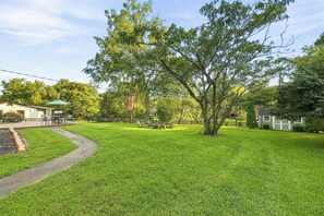 A well-maintained lawn with a paved path, a picnic table, and a small building with a green roof.