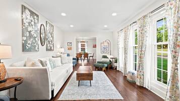A spacious living room with a sofa, a coffee table, and a dining area with chairs.